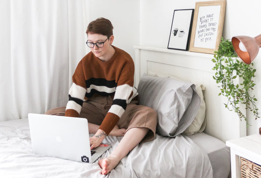 Adolescente a estudar na cama com computador portatil